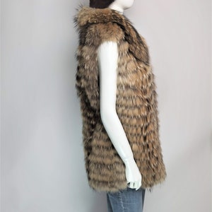 May include: A brown and tan fur vest with a sleeveless design. The vest is made of a soft, fluffy fur and has a long, flowing style.