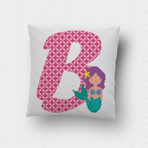 Puede incluir: Una letra B a cuadros rosa y blanca con una sirena de pelo morado y cola verde. La sirena lleva un sujetador de concha de mar morado y azul.