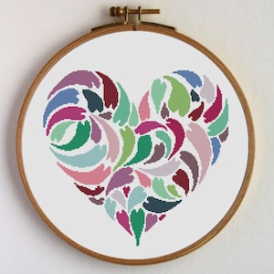 Peut inclure: Un motif de point de croix coloré d'un cœur composé de nombreuses petites formes tourbillonnantes dans des tons de rose, violet, vert, bleu et rouge.