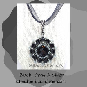 May include: Black, gray, and silver beaded pendant with a checkerboard design. The pendant is hanging from a black ribbon.