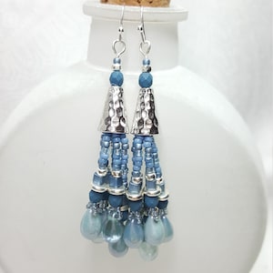 May include: Silver and blue beaded tassel earrings with a hammered metal cone at the top.