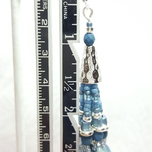 May include: Blue and silver beaded dangle earrings with a hammered metal cone charm. The earrings measure approximately 3 inches in length.