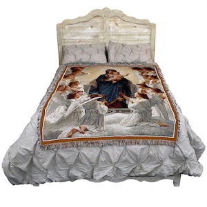 May include: A woven tapestry throw blanket featuring a religious image of the Virgin Mary holding baby Jesus surrounded by angels. The tapestry is displayed on a white bed with a wooden headboard.