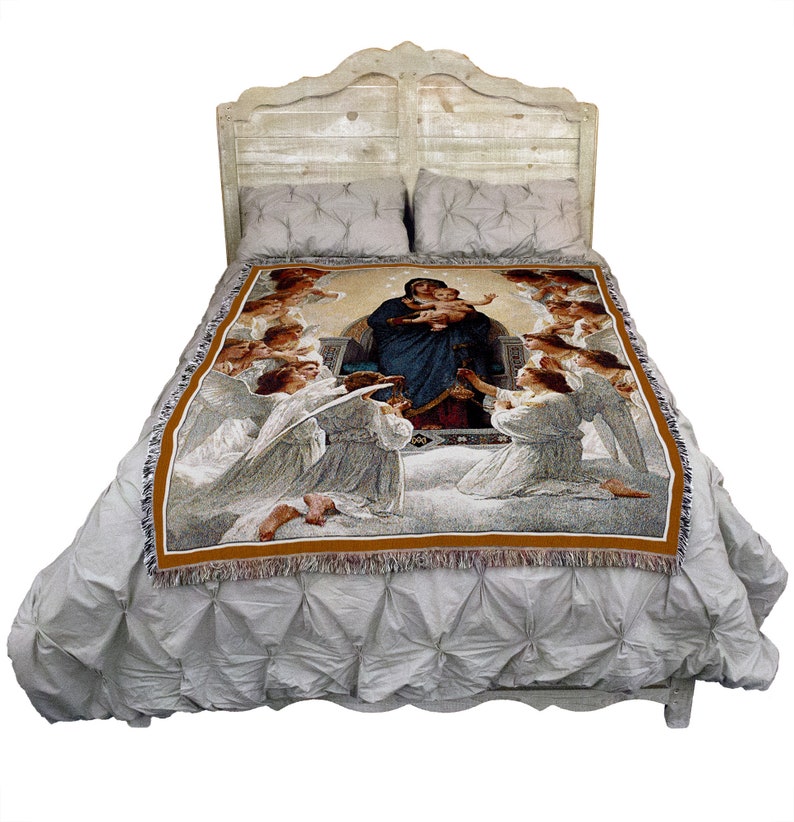 May include: A woven tapestry throw blanket featuring a religious image of the Virgin Mary holding baby Jesus surrounded by angels. The tapestry is displayed on a white bed with a wooden headboard.
