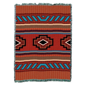 May include: A woven throw blanket with a Southwestern design. The blanket features a rust-colored background with geometric patterns in turquoise, brown, black, and cream. The edges are fringed with turquoise yarn.