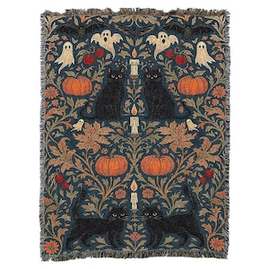 May include: A woven throw blanket featuring a dark blue background with a symmetrical pattern of black cats, orange pumpkins, white ghosts, bats, and lit candles. The design includes intricate orange and brown foliage, red berries, and fringed edges.