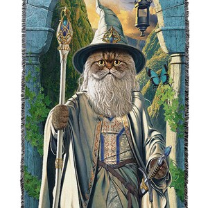 May include: Woven tapestry throw blanket featuring a cat dressed as a wizard. The cat wears a hat and robe, holding a staff and sword. The background depicts a fantasy landscape with a lantern and butterflies.
