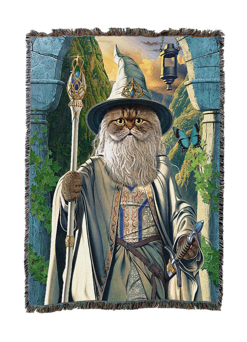 May include: Woven tapestry throw blanket featuring a cat dressed as a wizard. The cat wears a hat and robe, holding a staff and sword. The background depicts a fantasy landscape with a lantern and butterflies.