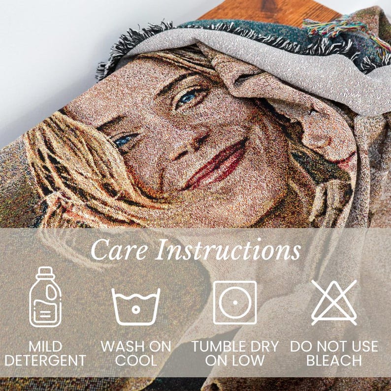 May include: Woven tapestry throw blanket featuring a portrait of a person with blonde hair and blue eyes. The blanket has a fringed edge and care instructions are displayed below the image. The care instructions include: mild detergent, wash on cool, tumble dry on low, and do not use bleach.