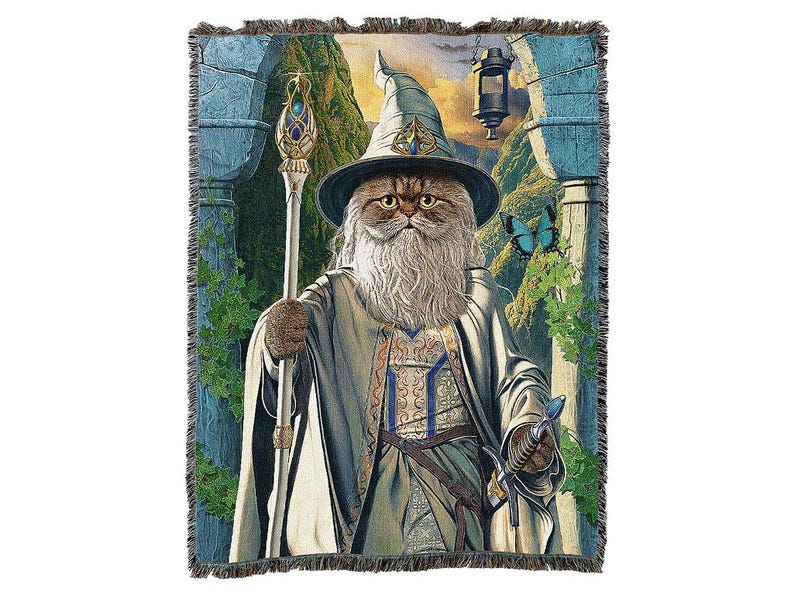 May include: Woven tapestry featuring a cat dressed as a wizard, complete with a hat, staff, and long white beard. The cat is set against a backdrop of a fantasy landscape with a lantern and a butterfly. The tapestry has a fringed edge.