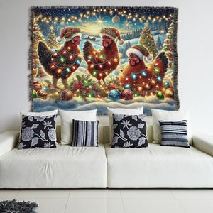 May include: A woven tapestry blanket featuring a festive winter scene with three brown chickens wearing Santa hats and wrapped in colorful string lights. The background displays snow-covered pine trees, glowing fairy lights, and Christmas ornaments.