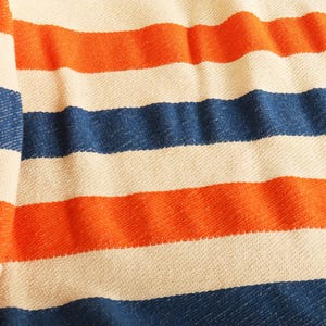 May include: A close-up of a woven textile with horizontal stripes in alternating colors. The stripes are in shades of orange, navy blue, and off-white. The fabric appears to be soft and textured, with visible weave details.