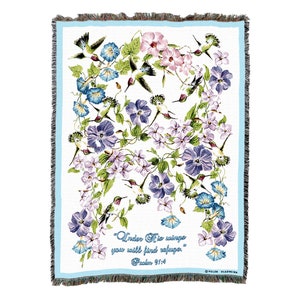 May include: A white woven throw blanket with a blue border. The blanket features a floral design with hummingbirds and the text "Under His wings you will find refuge." Psalm 91:4