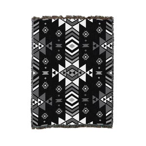 May include: Black and white woven throw blanket with a geometric pattern. The pattern features triangles, diamonds, and stripes.