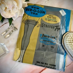 May include: A vintage packet of sheer micro mesh seamless stretch top hosiery in a yellow and blue colour scheme. The packet features a drawing of a woman wearing the hosiery. The text on the packet reads "New Ber-O-Lon Top", "Shear Micro Mesh Seamless 400 Needle 15 Denier", "S-T-R-E-T-C-H Top", "Ber-O-Lon", "First Quality", "34", "10%", "Tops for Real Comfort", and "Guaranteed First Quality".