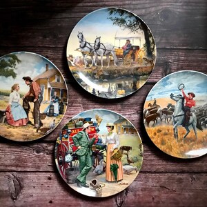 May include: Set of four decorative ceramic plates featuring vintage illustrations of cowboys, horses, and farm scenes. The plates are white with a glossy finish and feature colourful images.