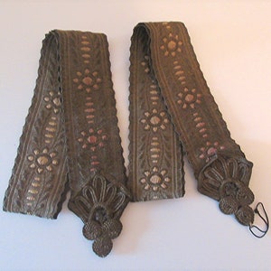 Peut inclure: Deux rubans décoratifs vintage. Les rubans sont vert olive foncé avec un motif floral doré et rose. Chaque ruban a une pièce d'extrémité décorative en métal.