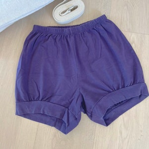 May include: Purple cotton shorts with a gathered elastic waistband and a wide leg.