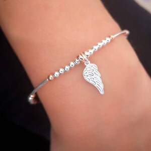 Puede incluir: Una pulsera de plata con un dije de ala de &aacute;ngel de plata. La pulsera est&aacute; hecha de peque&ntilde;as cuentas de plata y oro rosa.