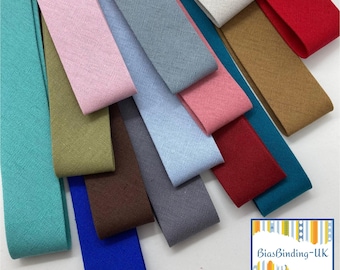 Op de afbeelding: Een verzameling kleurrijke schuine bandstroken in verschillende tinten, waaronder turquoise, roze, blauw en rood. De stoffen stroken zijn diagonaal gerangschikt en tonen hun verschillende tinten en texturen. De afbeelding bevat een logo rechtsonder.