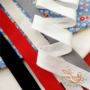 Könnte beinhalten: Sortiment an Stoffborten in verschiedenen Farben, darunter Schwarz, Rot, Weiß und Grau. Die Borten sind auf einem blauen und weißen Blumenstoff angeordnet. Der Text "FIND FABRICS" ist in der unteren rechten Ecke des Bildes sichtbar.