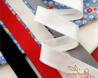 May include: Assortment of fabric trims in various colors, including black, red, white, and gray. The trims are arranged on a blue and white floral fabric background. The text "FIND FABRICS" is visible in the lower right corner of the image.
