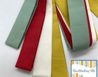 Puede incluir: Cinco colores diferentes de cinta de bies, incluyendo verde, rojo, blanco, amarillo y un azul claro. La tela está doblada por la mitad y dispuesta en forma de abanico. El texto "BiasBinding-UK" es visible en la esquina inferior derecha de la imagen.