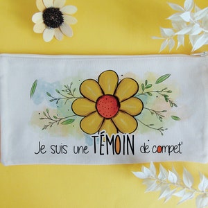 Puede incluir: Bolsa de maquillaje de lona blanca con una flor amarilla y hojas verdes. El texto "Je suis une témoin de compet'" está impreso en la bolsa.