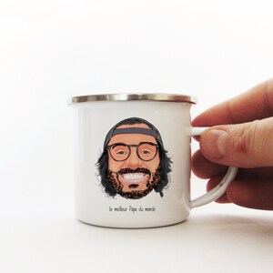 Peut inclure: Mug en émail blanc avec une illustration de dessin animé d'une personne portant des lunettes et un chapeau. Le mug a une poignée et le texte "le meilleur Papa du monde" en bas.