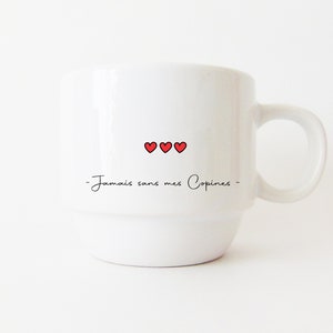May include: White ceramic mug with a black inscription that reads "Jamais sans mes Copines" and three red hearts.