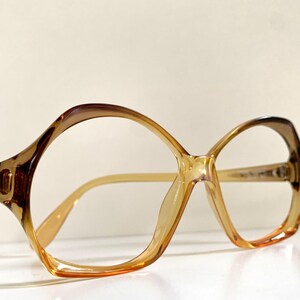 Puede incluir: Un par de gafas de plástico de color ámbar con una montura redonda octogonal.