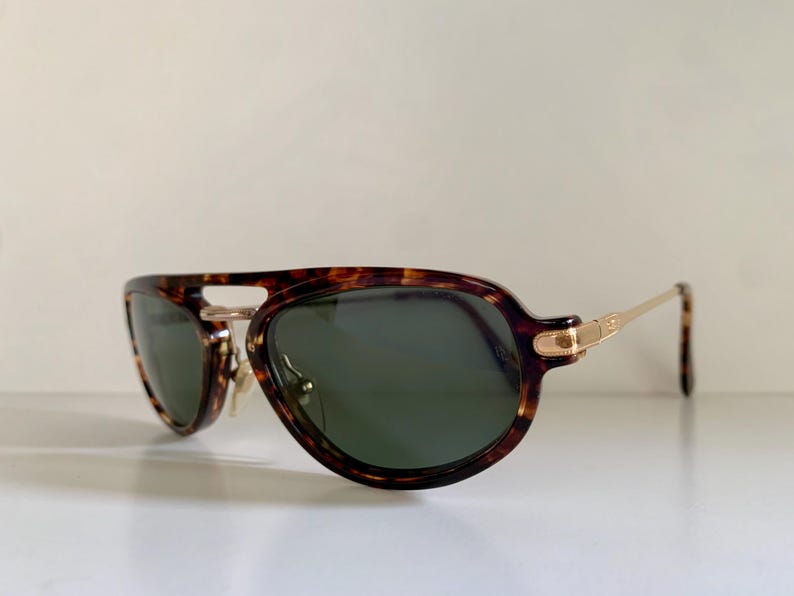 Puede incluir: Gafas de sol aviador de carey con detalles dorados y lentes verdes.