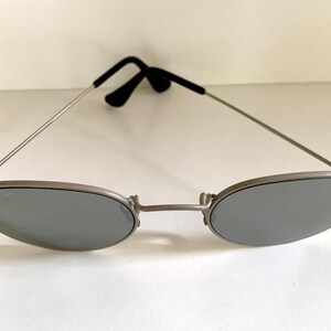 Puede incluir: Gafas de sol ovaladas plateadas con lentes espejados.