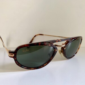Puede incluir: Gafas de sol Ray-Ban de carey con detalles dorados y lentes verdes. Las gafas tienen un estilo aviador cl&aacute;sico.