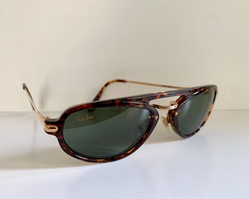 Puede incluir: Gafas de sol Ray-Ban de carey con detalles dorados y lentes verdes. Las gafas tienen un estilo aviador cl&aacute;sico.