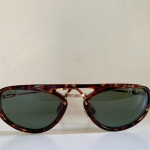 Puede incluir: Gafas de sol aviador de carey con detalles dorados y lentes verdes.