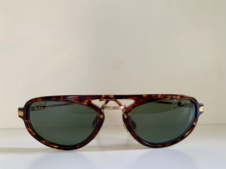 Puede incluir: Gafas de sol aviador de carey con detalles dorados y lentes verdes.