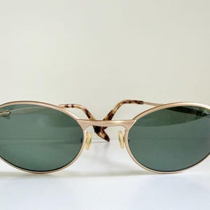 Puede incluir: Gafas de sol ovaladas con montura dorada y lentes verde oscuro. Las patillas presentan un dise&ntilde;o de carey. Un accesorio elegante para la protecci&oacute;n ocular, con un dise&ntilde;o cl&aacute;sico.