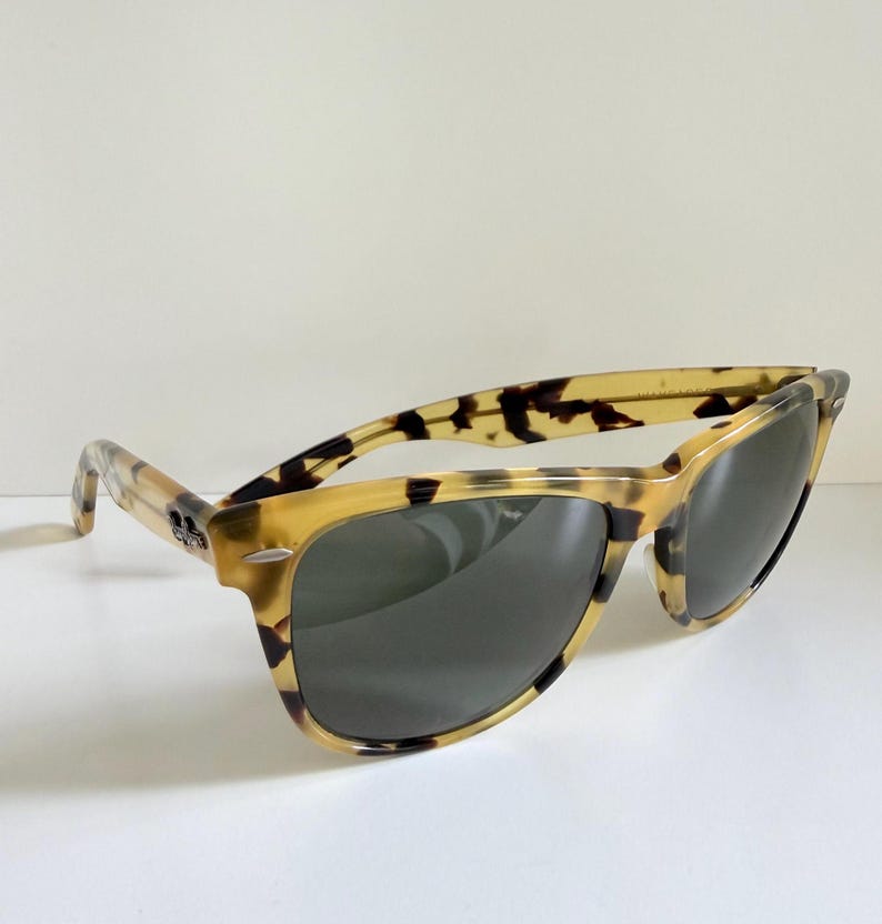 May include: Tortoiseshell sunglasses with dark lenses. The frames have a classic design with a speckled pattern in shades of brown and tan. The sunglasses are angled slightly, showcasing the shape and style.