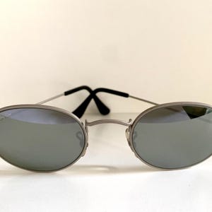Puede incluir: Gafas de sol ovaladas plateadas con lentes espejados.