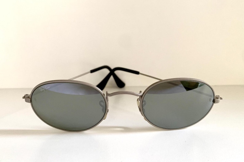 Puede incluir: Gafas de sol ovaladas plateadas con lentes espejados.
