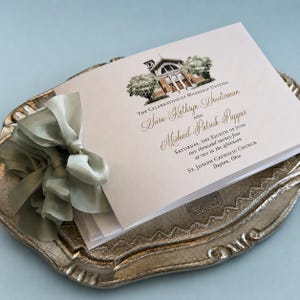 May include: A wedding invitation card featuring a watercolor illustration of a church, with text reading The Celebration of Marriage Uniting Sara Kathryn Sweetorman and Michael Patrick Pappas, Saturday, the eighth of June, St. Joseph Catholic Church.