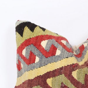 May include: A colorful throw pillow with a geometric pattern in shades of red, green, blue, and yellow. The pillow is made of woven fabric and has a traditional design.