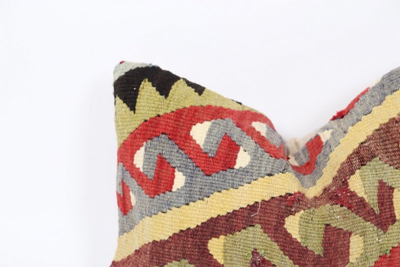 May include: A colorful throw pillow with a geometric pattern in shades of red, green, blue, and yellow. The pillow is made of woven fabric and has a traditional design.