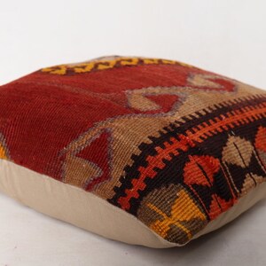 May include: A red, orange, brown, and beige patterned throw pillow with a white cotton backing.