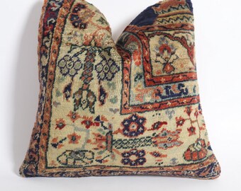 May include: A decorative pillow with a traditional Persian rug design. The pillow is made of a soft, woven fabric with a cream background and intricate patterns in shades of red, blue, and green.