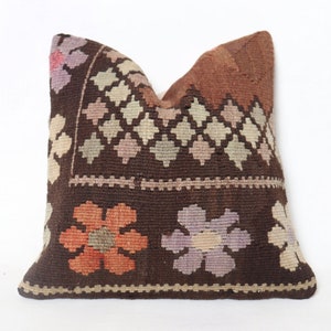 Peut inclure: Un coussin de décoration brun et beige à motifs floraux. Le coussin est en tissu tissé et a une bordure frangée.