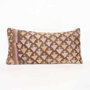 May include: A long rectangular pillow with a brown and pink geometric pattern. The pillow is made of a soft, woven fabric and has a traditional design.