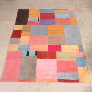 May include: A colorful patchwork rug with squares of red, pink, orange, yellow, blue, brown, and gray.