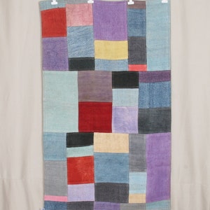 May include: A patchwork rug with squares of different colors, including red, blue, purple, yellow, and gray.